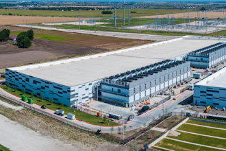 Aerial view of modern industrial warehouse and logistics facility complex with blue and white buildings in rural landscape