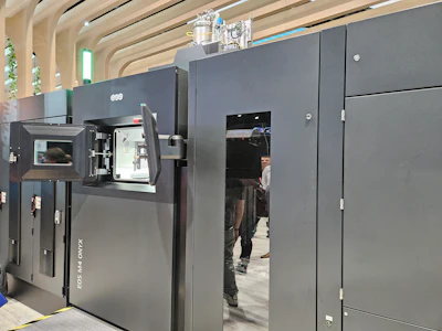Industrial 3D printing machine with open chamber door in modern showroom setting