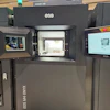 3D printer with open chamber displaying printing platform and control interface