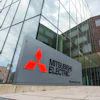 Mitsubishi Electric logo on gray exterior building sign at corporate headquarters entrance
