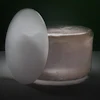 White egg-shaped object beside a translucent jar on dark background