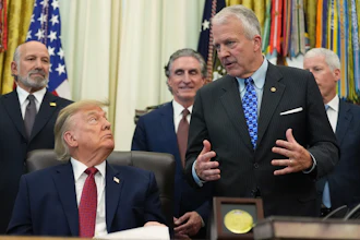 Formal meeting in the Oval Office with government officials and American flags in background