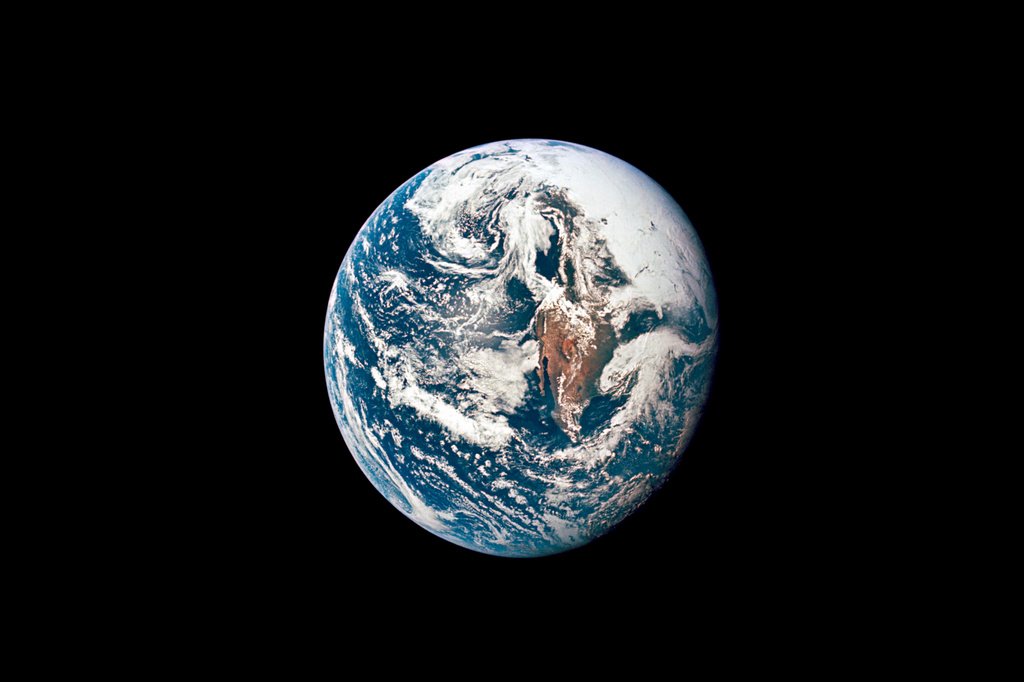Earth viewed from space showing blue oceans, white clouds, and continental landmasses against black background