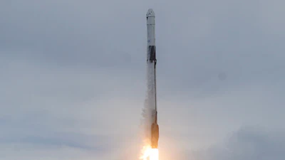 Rocket launching vertically with bright orange flame exhaust against cloudy sky