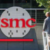 TSMC logo displayed on building exterior signage with person walking past
