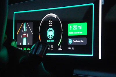 Vehicle dashboard display showing 55 mph speed, navigation arrow for 20 miles, and eyes-free active safety features with cyan neon styling
