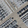 Aerial view of a large parking lot with hundreds of white, gray, and black vehicles arranged in organized rows