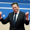 Man in black suit with fist gestures against patriotic blue background with stars
