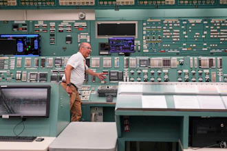 Technician operating control room with extensive monitoring equipment and instrument panels