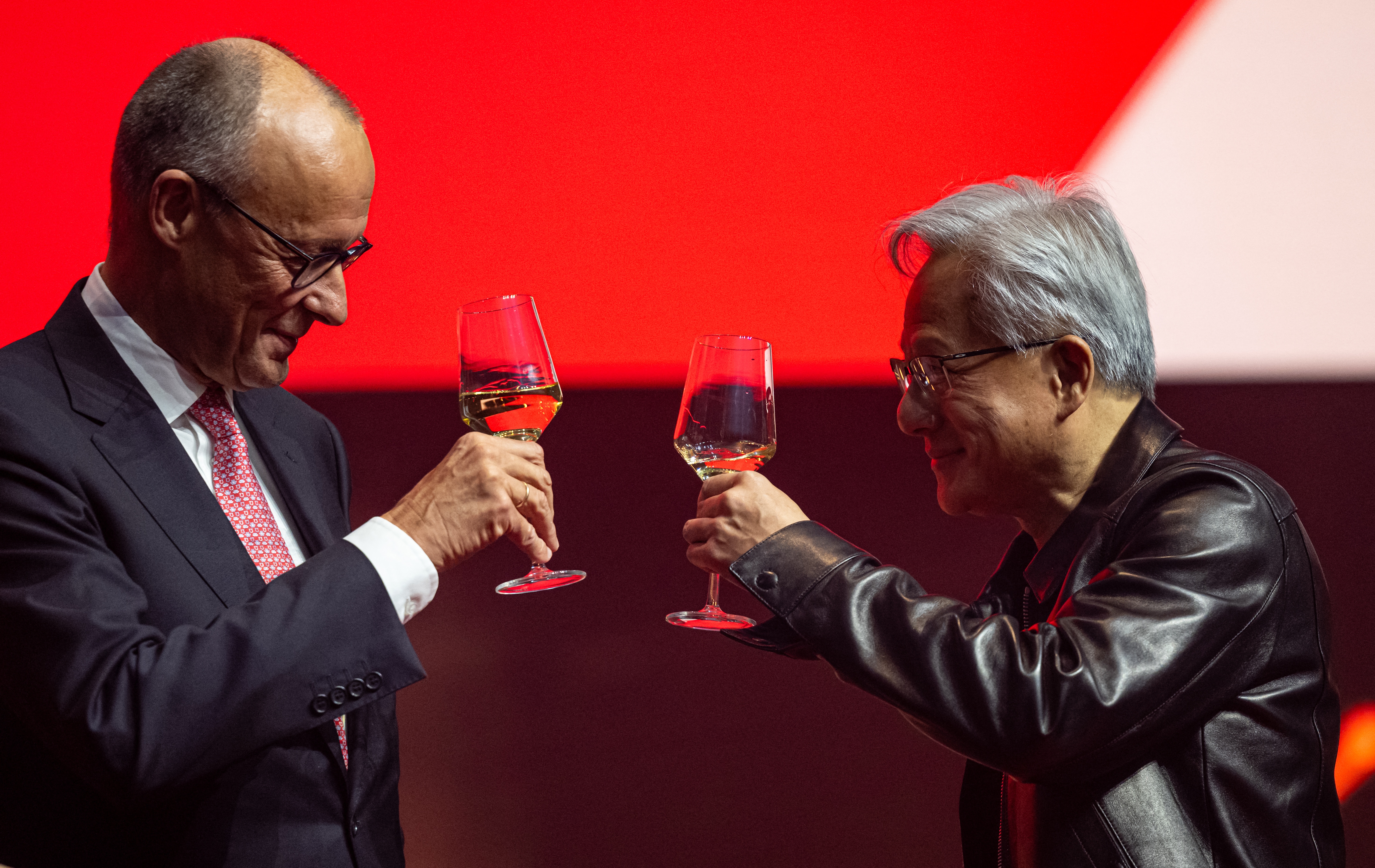 Two professionals toasting with glasses of whiskey against a red background during a formal event