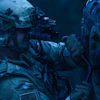 Tactical operator in full combat gear with rifle and night vision equipment in blue-toned lighting