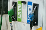 Green and blue fuel pump nozzles labeled Petrol and Diesel at a gas station dispenser