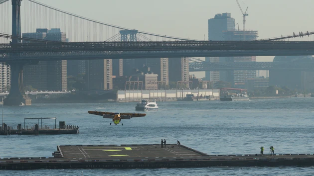 Seaplane landing on East River near Manhattan Bridge with NYC skyline in background