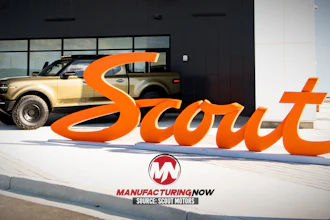 Scout Motors orange brand signage displayed outside showroom with tan SUV and Manufacturing Now logo