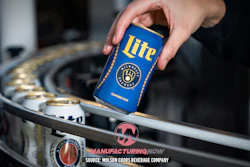 Hand holding blue Miller Lite beer can above industrial manufacturing equipment