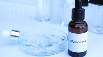 Glycolic acid bottle with dropper in laboratory setting with petri dish and test tubes