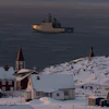 Arctic coastal settlement with red church, snow-covered buildings, and icebreaker ship in Greenlandic waters