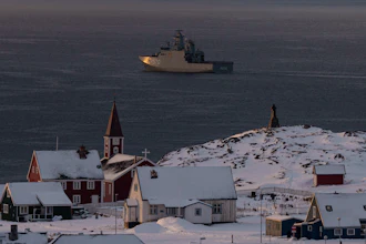 Arctic coastal settlement with red church, snow-covered buildings, and icebreaker ship in Greenlandic waters