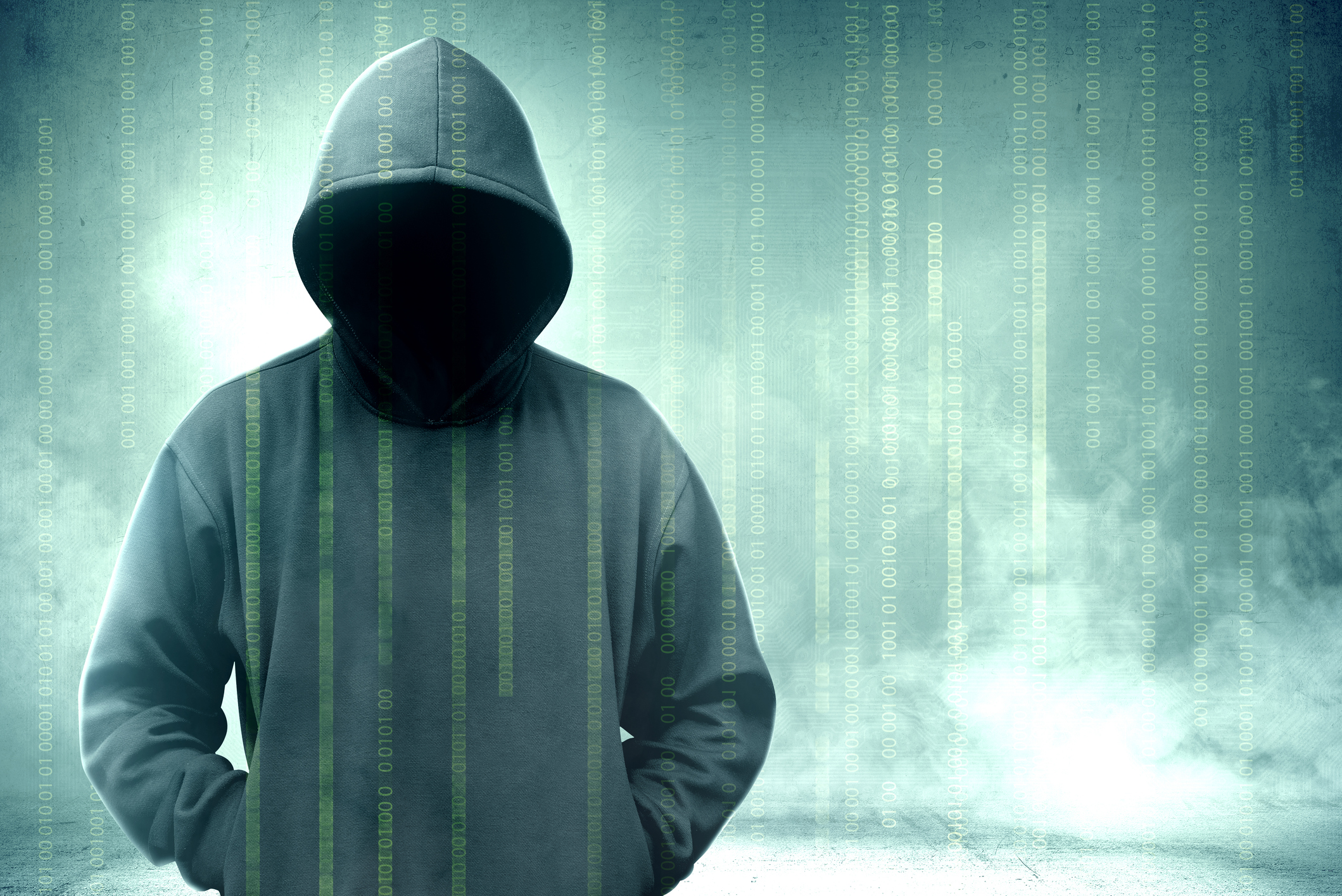 Hooded figure silhouette with digital binary code overlay on teal background representing cybersecurity and hacking