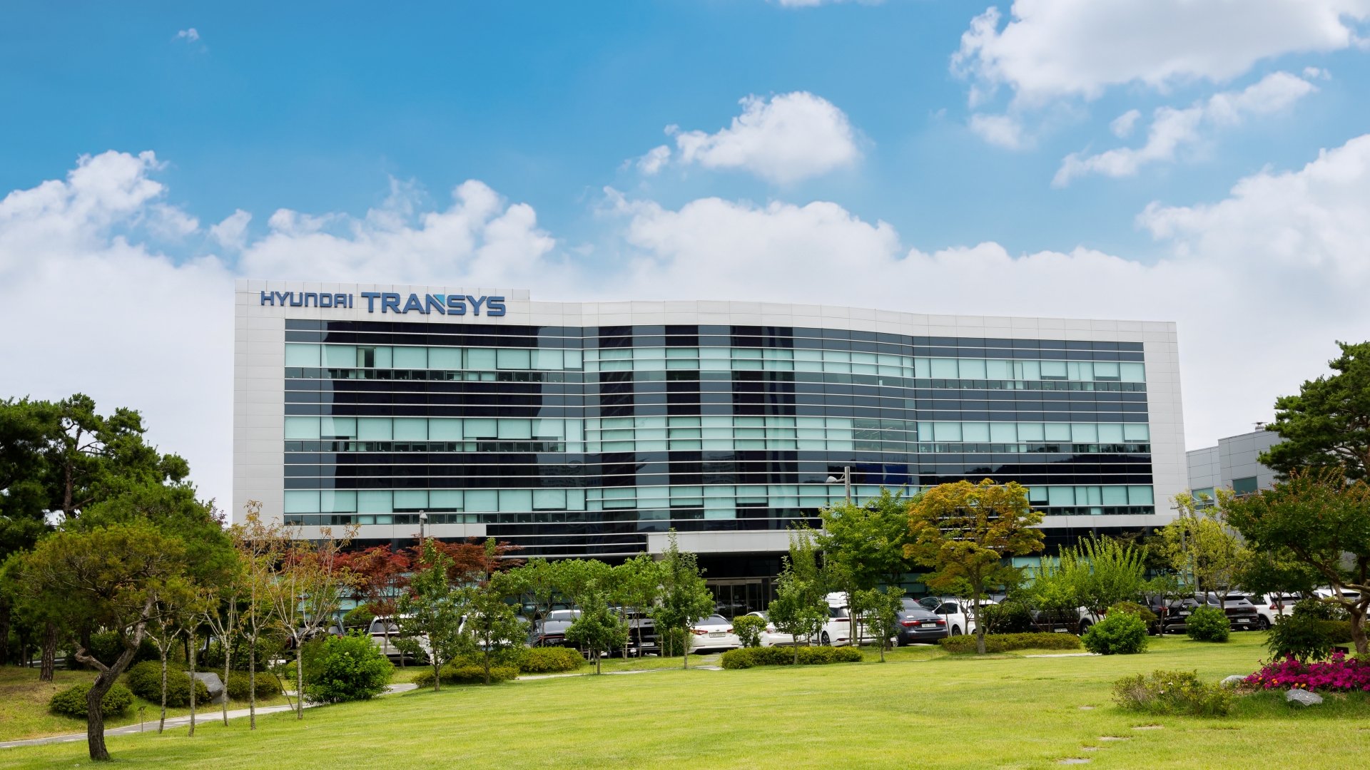 Hyundai Transys modern corporate headquarters building with glass facade and landscaped grounds under blue sky