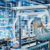 Female factory worker in safety gear photographing industrial equipment in modern manufacturing facility