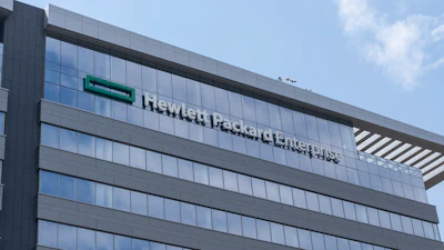 Modern glass and steel office building with company signage on facade under blue sky