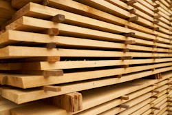 Stacked wooden planks with natural grain texture stored in a warehouse or lumber yard