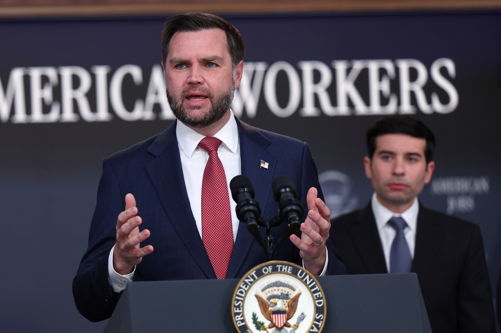 Man in navy suit speaking at podium with Presidential Seal, addressing audience at American Workers event