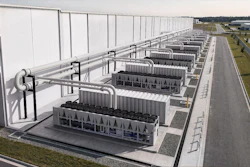 Industrial facility with rows of large rectangular structures under white roof framework and connecting piping systems