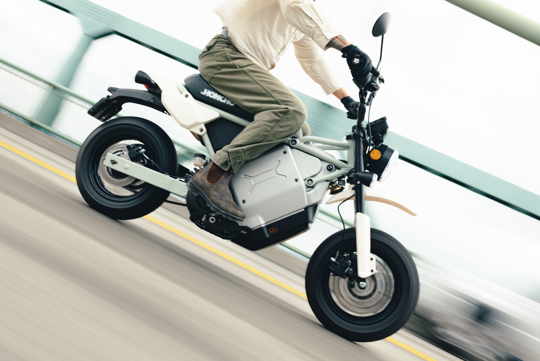 Person riding white and black electric scooter on road with yellow lane marking