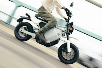 Person riding white and black electric scooter on road with yellow lane marking