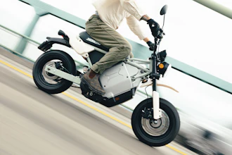 Person riding white and black electric scooter on road with yellow lane marking
