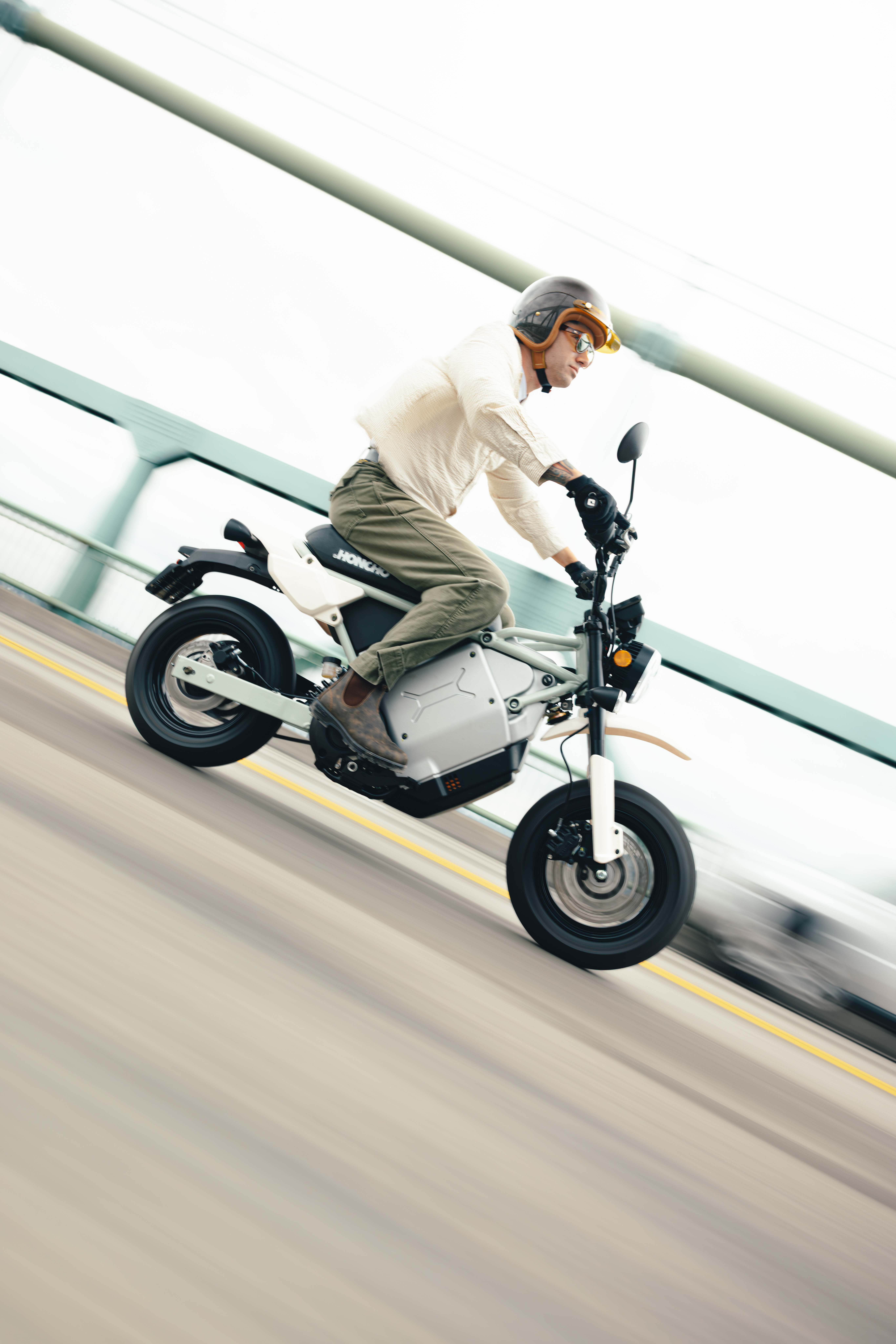 Man in casual wear riding white electric scooter on ramp wearing yellow helmet and sunglasses