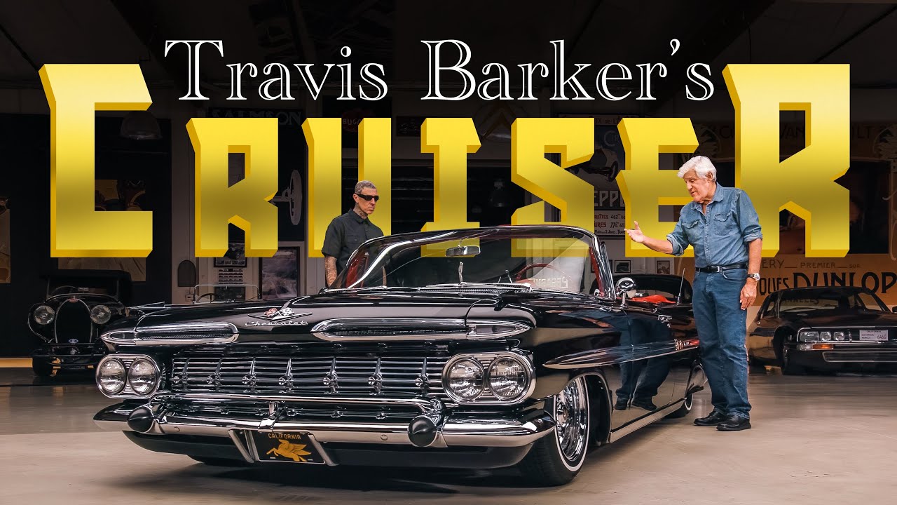 Travis Barker's classic black convertible cruiser displayed in showroom with two men standing beside the vintage 1950s car