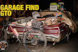 Garage find collection featuring red bicycle, car door panel, tools, and Arai helmet box on workbench