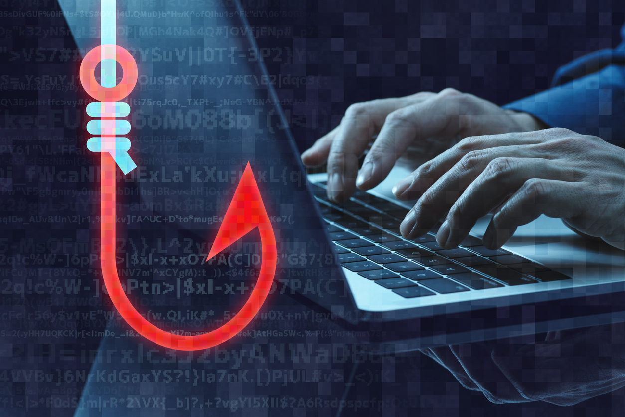 Red phishing hook icon with code and hands typing on laptop representing cybersecurity threat