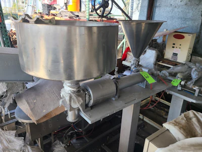 Industrial stainless steel mixing tank with motor and funnel attachment in workshop facility