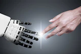 Human hand reaching toward robotic hand in a gesture of connection and collaboration against a gray background with light rays