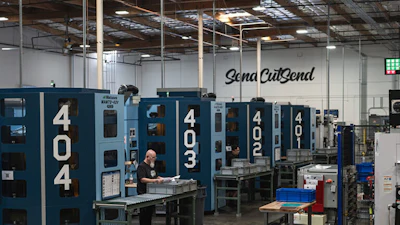 Industrial manufacturing facility with blue CNC machines and Sena CutSend signage on warehouse wall