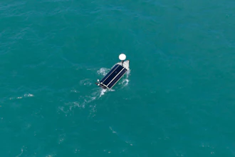 Aerial view of a pontoon boat on clear turquoise water with white canopy