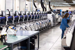 Industrial warehouse facility with rows of automated sorting machines and a worker in blue uniform monitoring operations