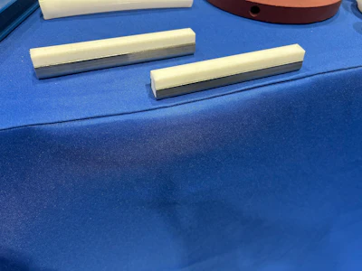 Two cream and metallic gray rectangular drawer handles displayed on blue fabric surface