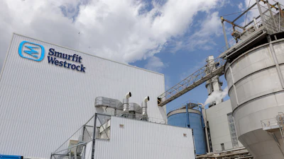 Smurfit Westrock industrial manufacturing facility with blue logo on corrugated metal building and storage tanks