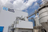 Smurfit Westrock industrial manufacturing facility with blue logo on corrugated metal building and storage tanks