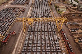 Aerial view of busy shipping port with hundreds of stacked containers, yellow gantry cranes, and cargo handling equipment