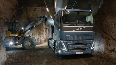 Volvo truck and wheel loader operating in an underground tunnel construction site with bright LED lighting