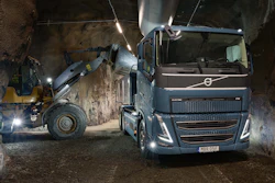 Volvo truck and wheel loader operating in an underground tunnel construction site with bright LED lighting