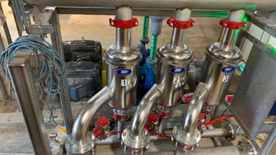 Industrial stainless steel multi-valve manifold system with red handles mounted on frame in workshop